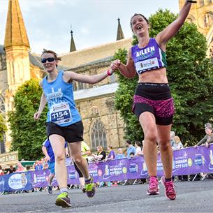 Female runners crossing the finish line of the Durham City Run