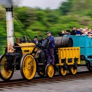 Locomotive pulling a coach pulling a crowd of people