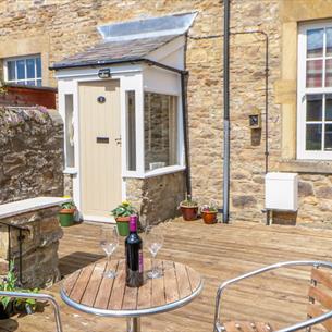 Old Workhouse image of garden patio with a small table and chairs with a bottle of wine