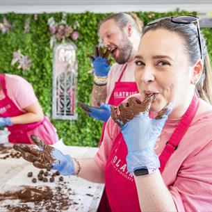 A woman is licking chocolate off her fingers, while participating in a chocolate making workshop.