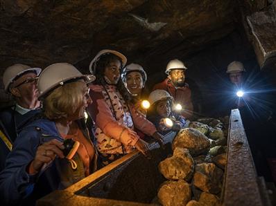 Children wearing hard hats in Killhope Lead Mine in dark truck full of rocks