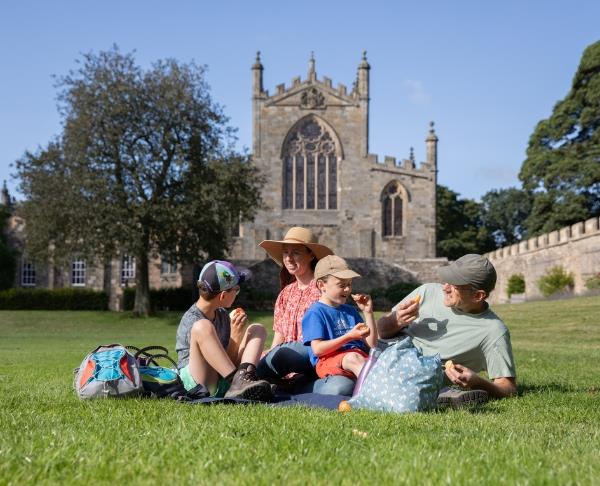 A family sat on the grass in front of Auckland Castle