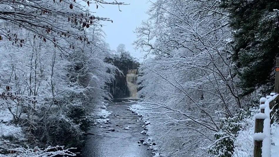 A frosty, snowy day with High Force waterfall in the distance.