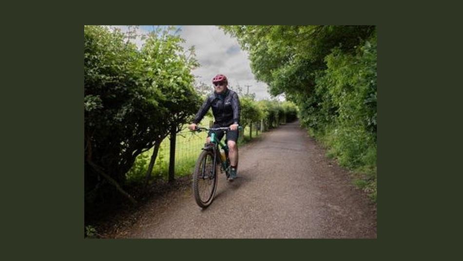 A man riding a bike along a single track road in the countryside