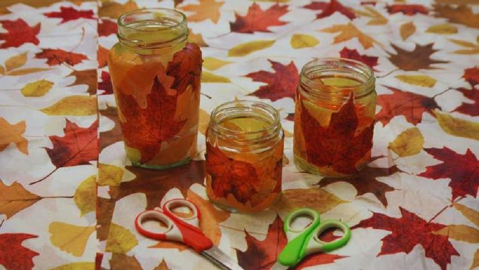 Leafy Lanterns at Ushaw. Jars with autumnal leaves in them, placed on a table with a leafy patterned tablecloth.