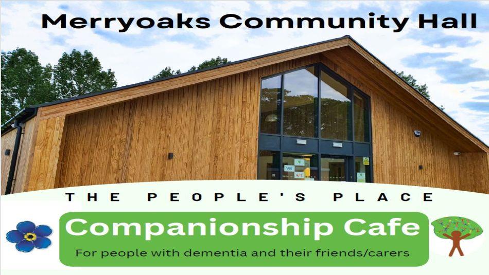 A wooden building on a sunny day with the text reading, 'Merryoaks Community Hall, The People's Place, Companionship Cafe.'