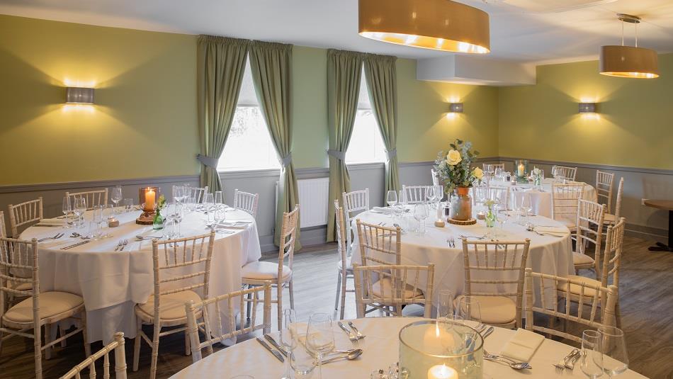 Dining room set out with round tables with white tablecloths, white chairs and table settings