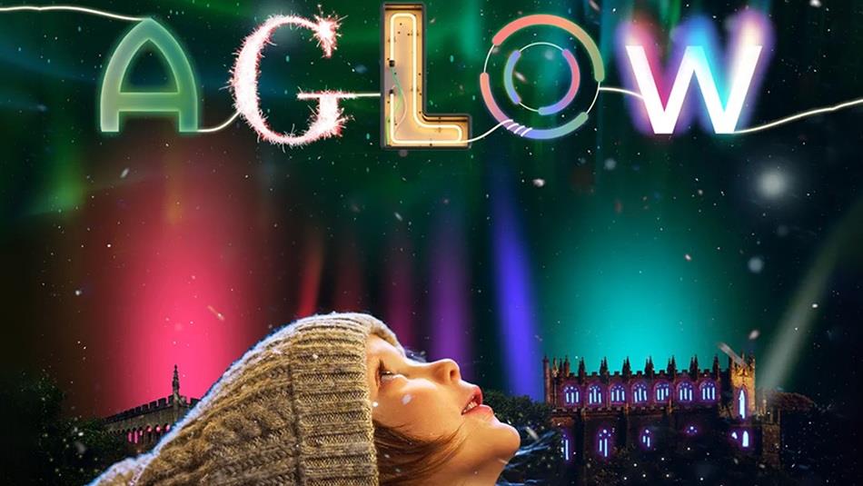 Aglow Auckland Palace & Gardens. A child in a wool hat looks upwards at the colourfully lit sky.