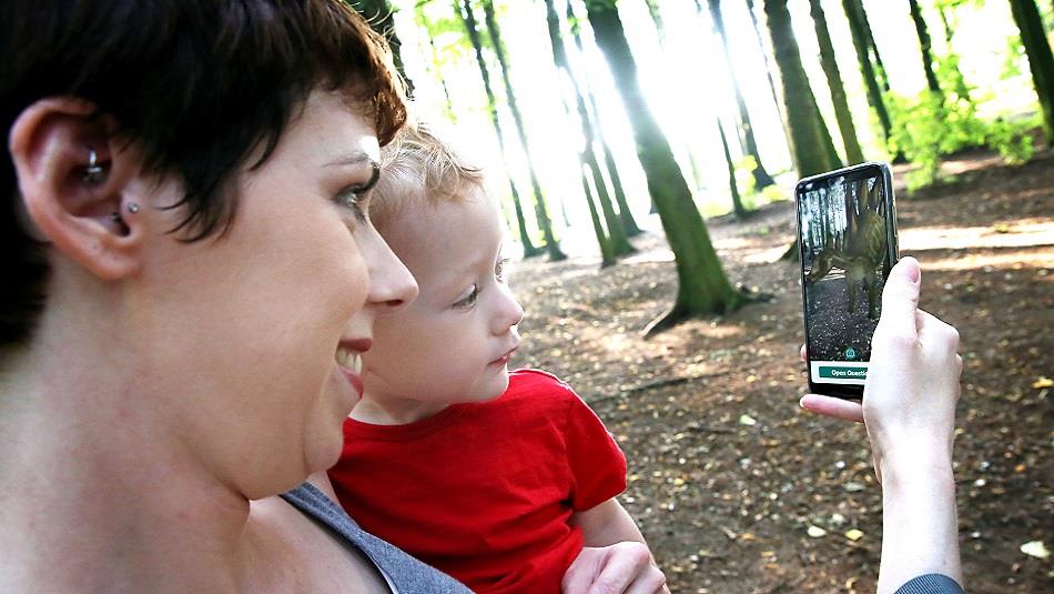 Woman with child looking at App on a mobile phone, forest setting