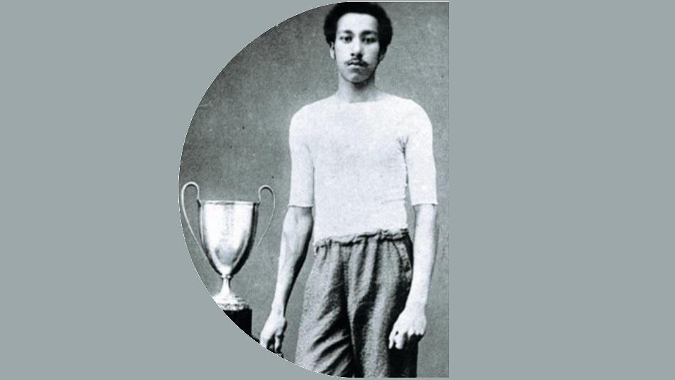 Arthur Wharton standing beside a football trophy