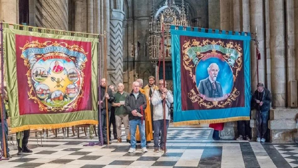 A group of people displaying Miners Banners in Durham Cathedral