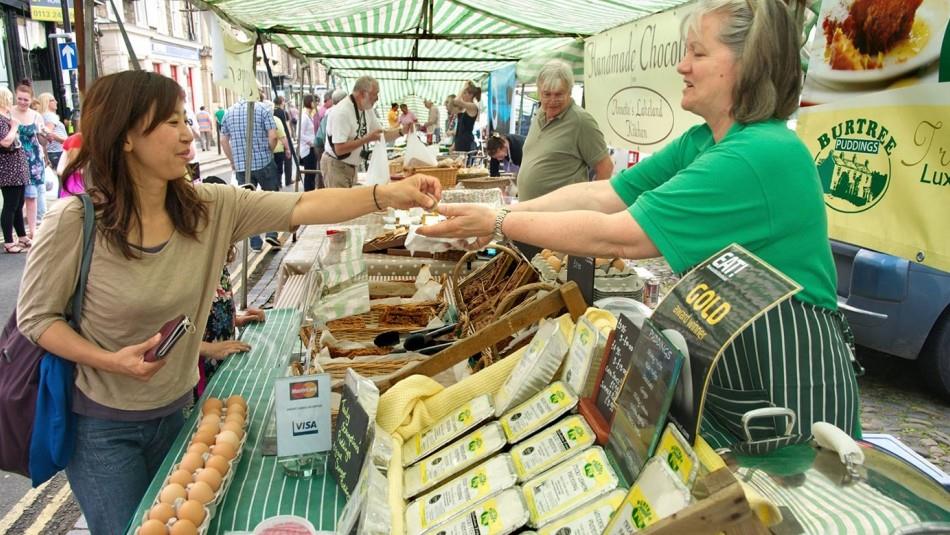 Trader at Barnard Castle Farmer's Market at stall taking money from customer