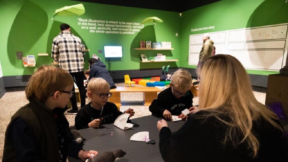 Children and an adult sitting around a table crafting with paper