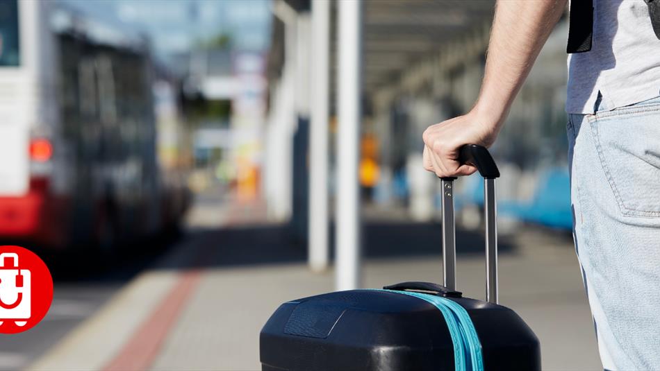 A person holding a suitcase in a bus station