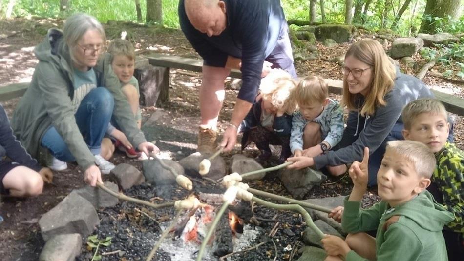 Adults and children sitting around a campfire toasting Marshmallows