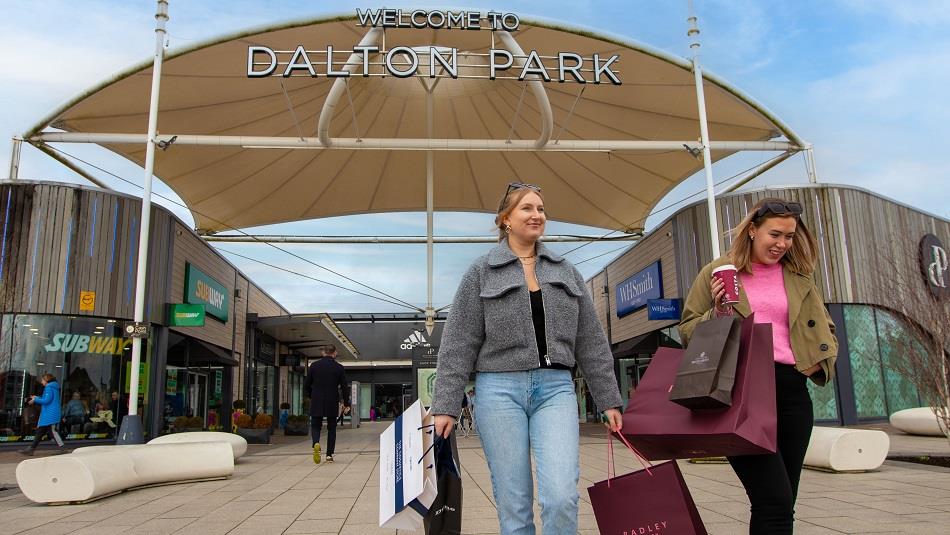 Shoppers leaving Dalton Park Outlet and Outdoors with lots of bags, smiling.