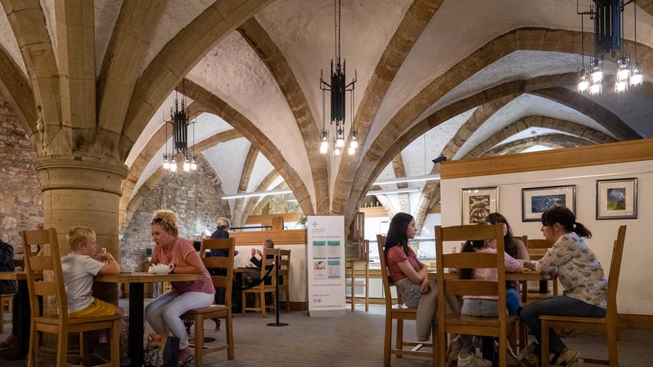 Two families sit at tables in a cafe, which has an arched stone roof.