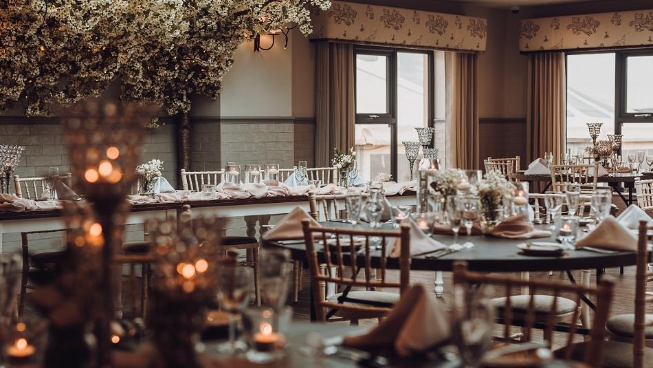 The Orangery, with friendly folk pelmets, soft grey ticking curtains, lime-washed furniture, and clothed tables with floral centrepieces and candles.