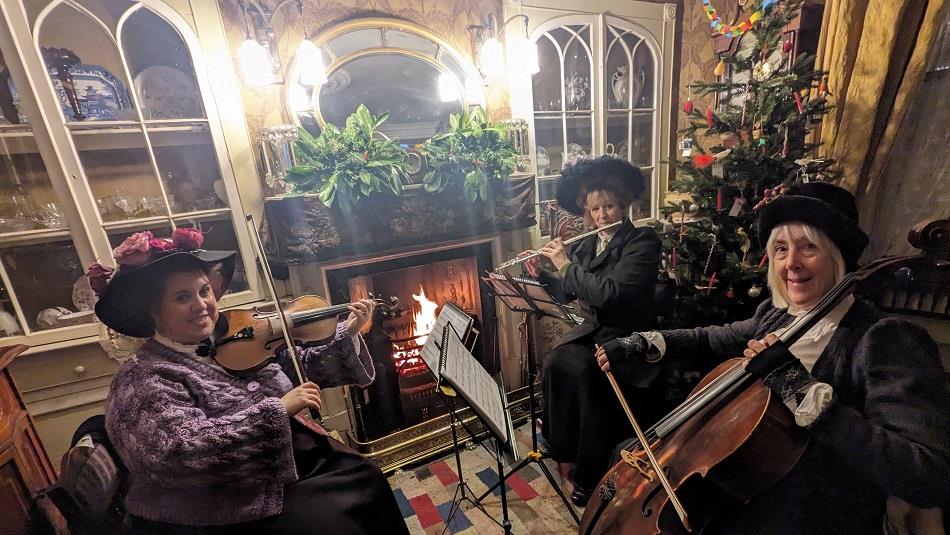 People in period dress, playing instruments by the Christmas Tree at Beamish Museum