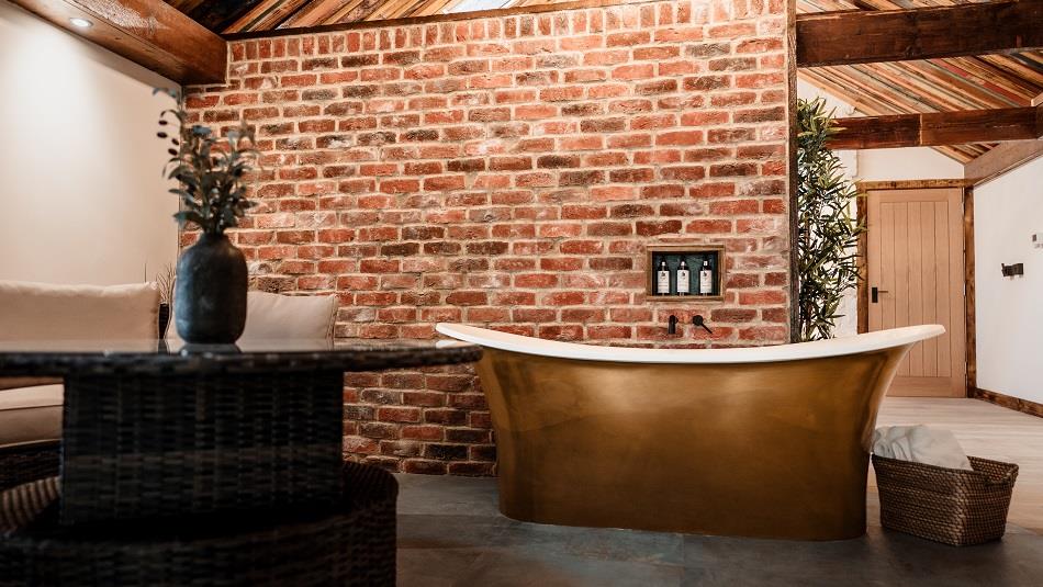 High ceilings, wood panelling, bespoke candle chandeliers and a large free-standing bath against the exposed brick wall.