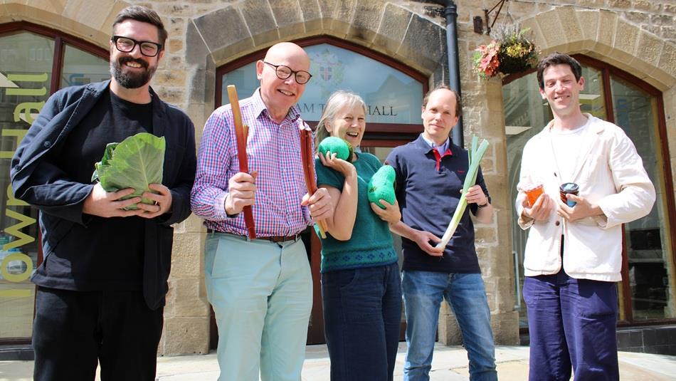 Staff standing outside of Durham Town Hall smiling, holding vegetables.
