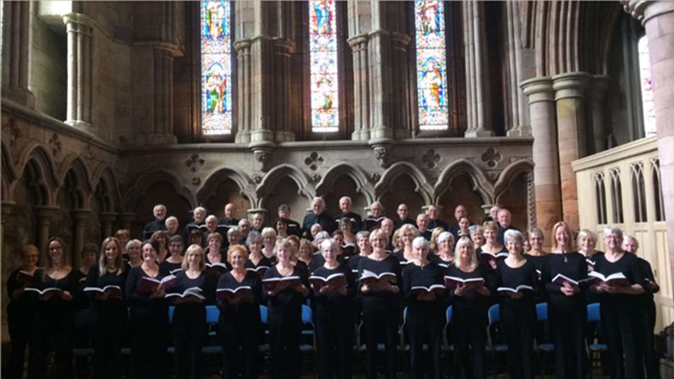 Altrincham Choral Society performing together in a beautiful church with colourful stained glass windows.