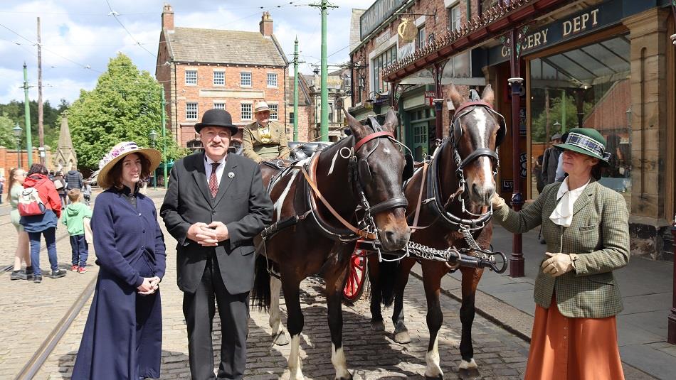 People in period dress stand beside two horses