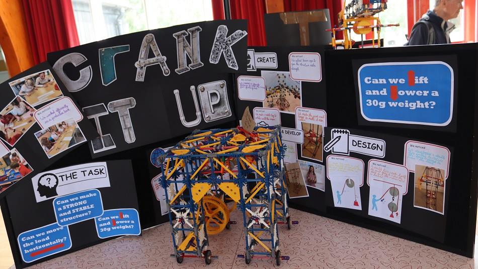 Engineering and maths-related activities in front of a sign which reads, 'Crank It Up!'