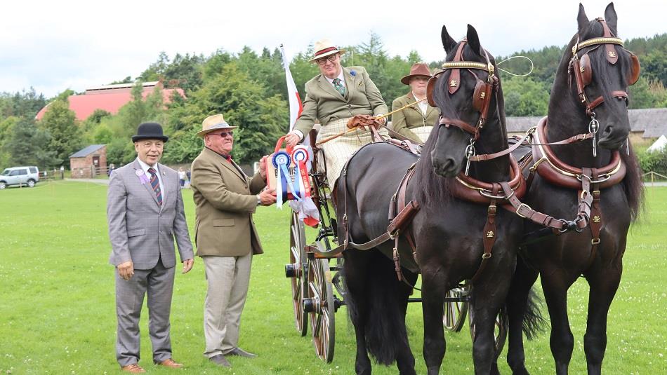 People sitting in a carriage drawn by two beautiful black horses at Beamish Museum