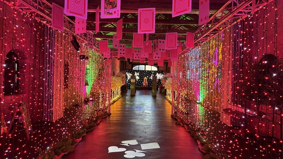 Playing cards suspended from beams in an illuminated, colourful tunnel
