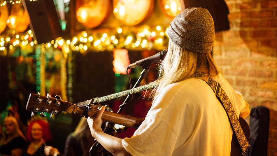 A musician playing guitar and singing to an audience at Katie O'Brien's.