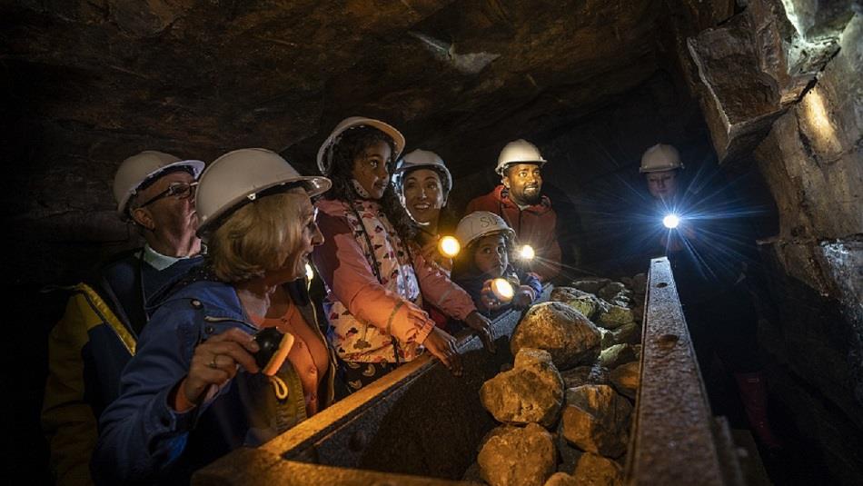 Children wearing hard hats in Killhope Lead Mine in dark truck full of rocks