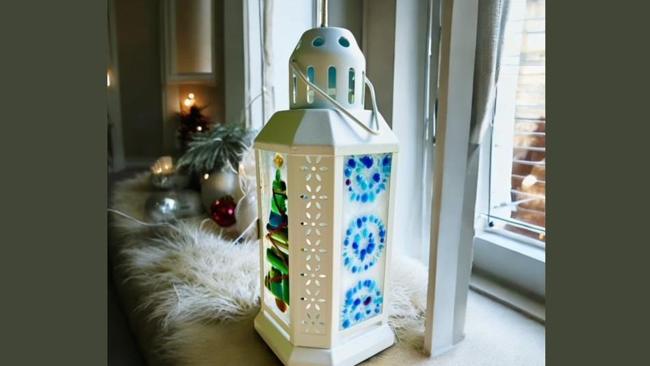 A white lantern with a fused glass design on glass panels