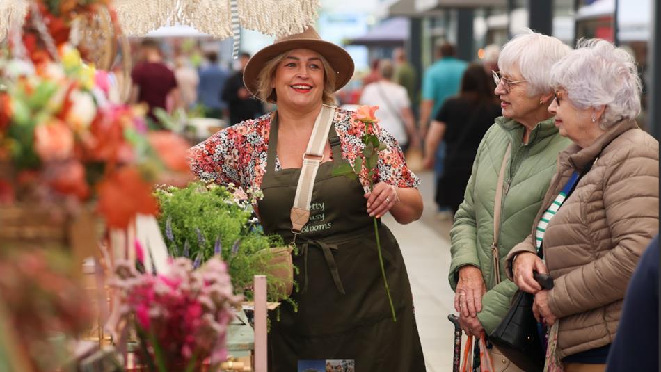 People visiting a colourful flower stall at the Artisan Market at Dalton Park Outlet and Outdoors.