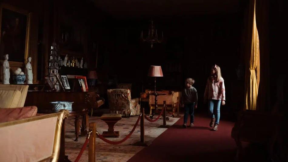 Two children walking in a dark room at Raby Castle