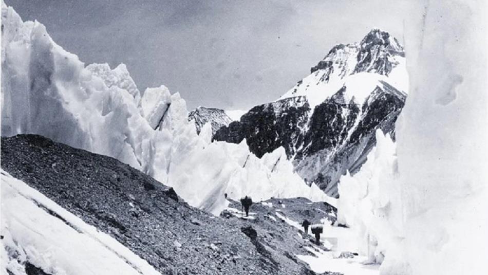 Black and White photograph of Everest with walkers.  'Passing through the "Trough" enroute to camp 3' from the Bentley Beetham Collection