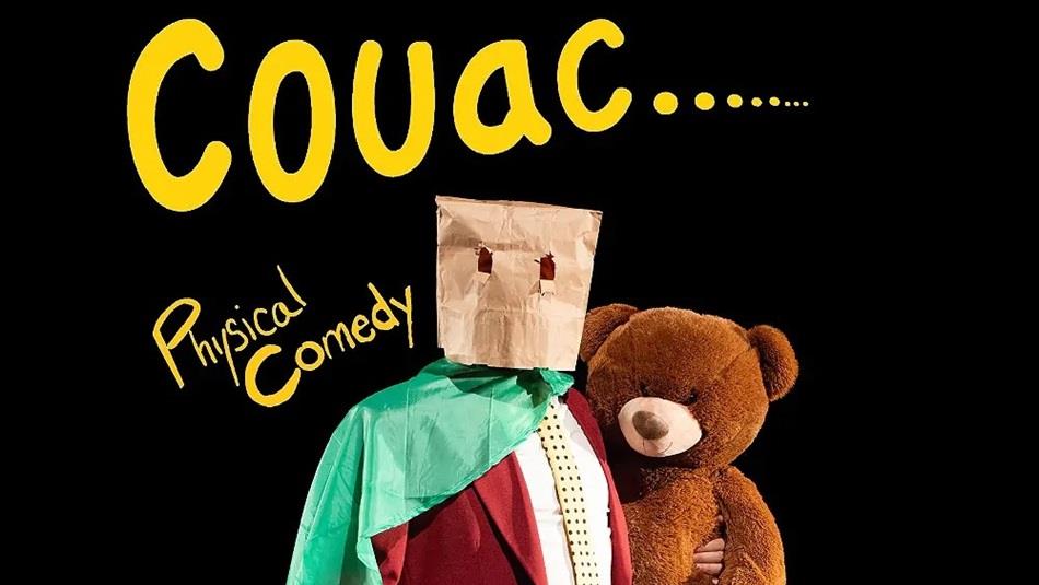 person wearing a suit with a green cape, a brown paper bag on head, holding a teddy bear