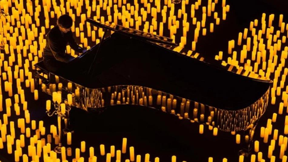 Someone playing a grand piano surrounded by lit candles