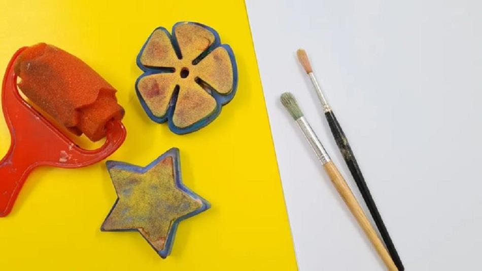 Two paint brushes, a flower and star shape for printing with paint and a print roller