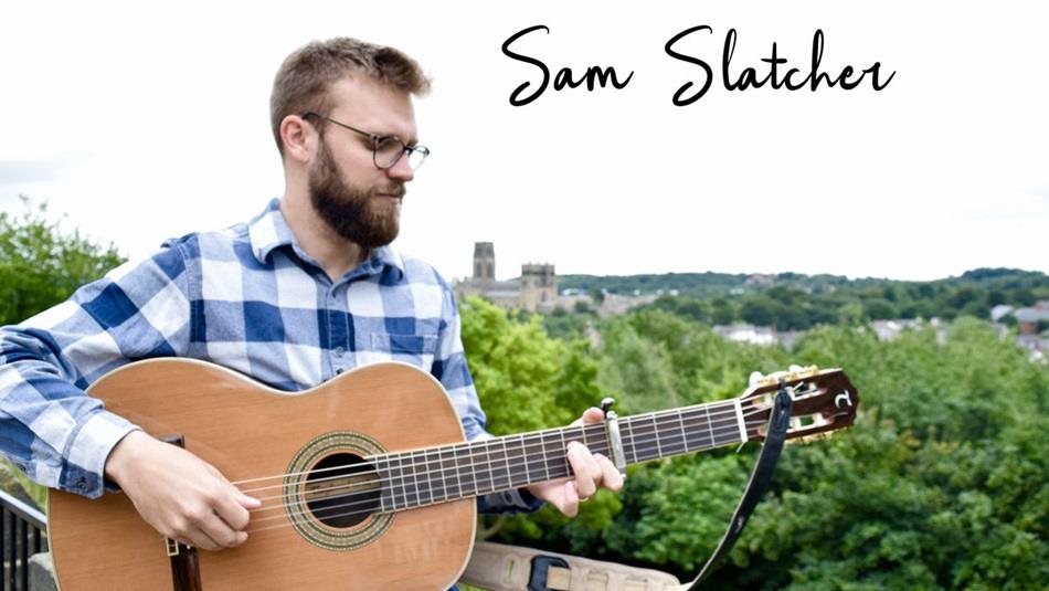 Sam Slatcher, musician, playing guitar with Durham Cathedral in the distance.