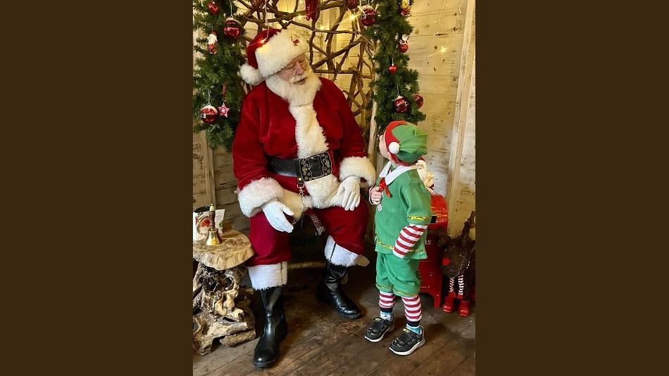 Child dressed as a Christmas Elf visiting Santa