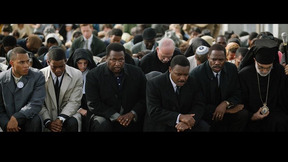 a crowd of people with their heads bowed, praying