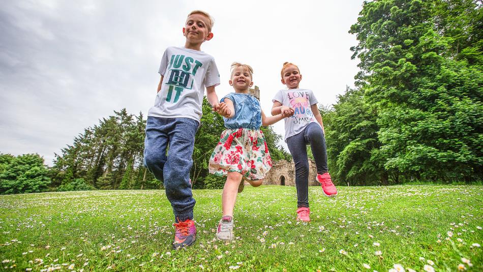 Group of children holding hands running towards camera at Hardwick Park.