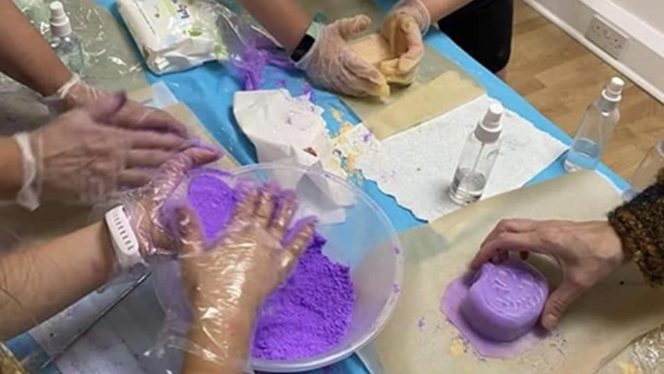 People wearing clear gloves mixing purple bathbombs at Lanchester Garden Centre.