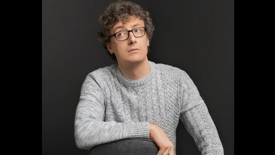 Luke Connell resting his arm on a chair and glancing sideways.