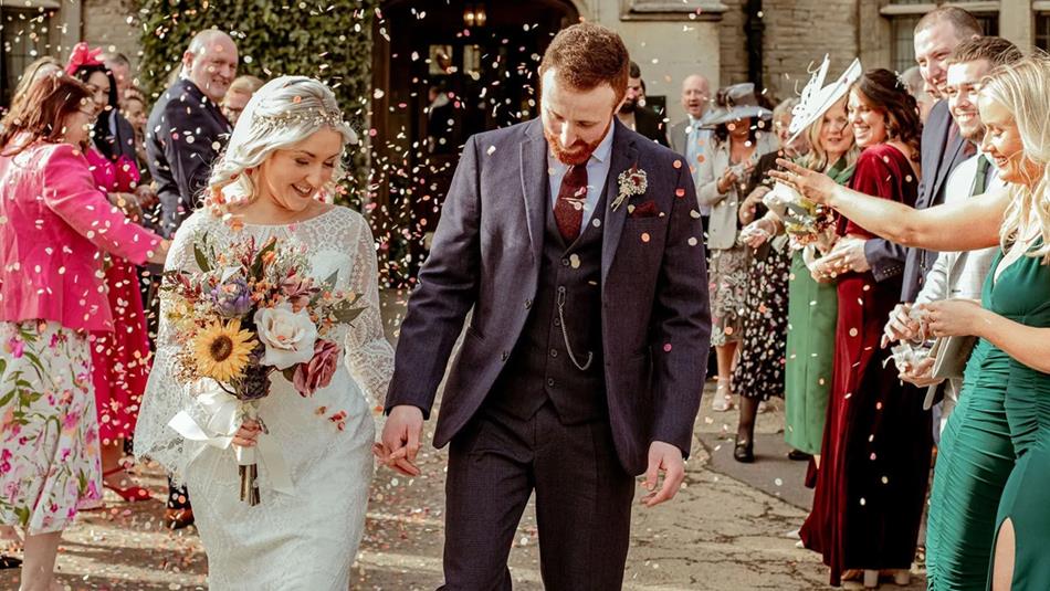 Wedding guests throwing confetti over newly married couple.