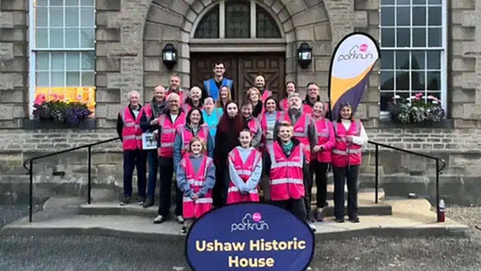 A group of parkrun volunteers in pink jackets outside Ushaw Historic House, Chapels and Gardens.