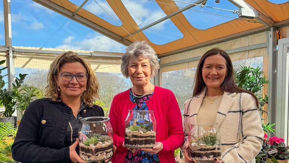 Three people holding succulent-based terrariums at South Causey Inn