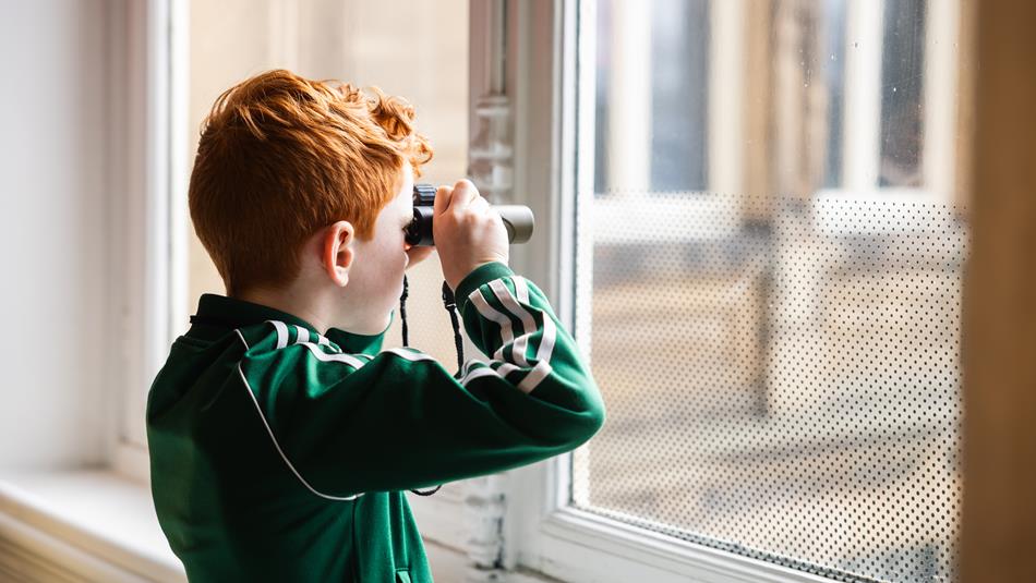 Little boy in green jacket, peering into binoculars - Nature Spotters at The Bowes Museum