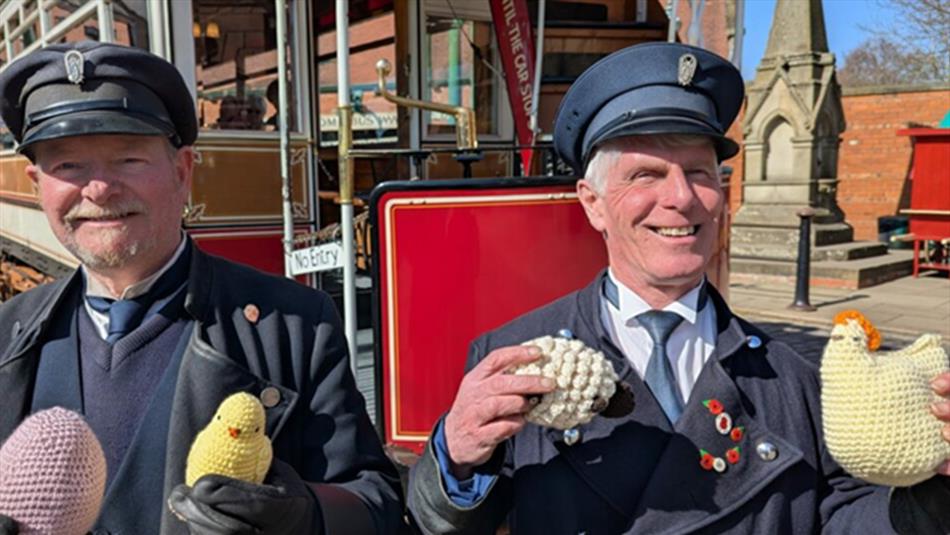 Two members of staff holding knitted Easter items such as eggs, chicks, and hens.